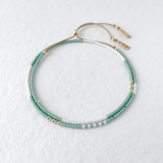 double wrap beaded delicate bracelet on a beige silk with matt aqua green and white glass beads with gold fill accent beads and slider to adjust the fit