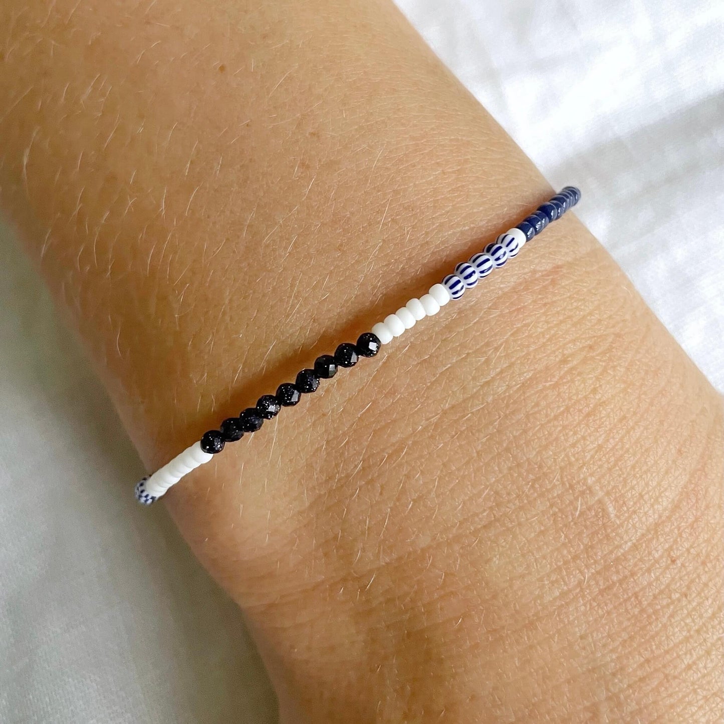 Gold-fill bracelet with navy, white and sandstone glass beads worn on a wrist