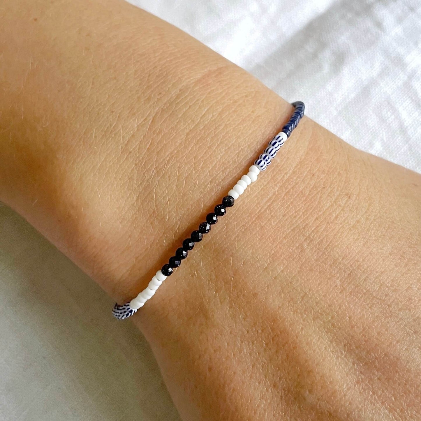 Bracelet with navy and white beads on a wrist worn on the wrist against a white background