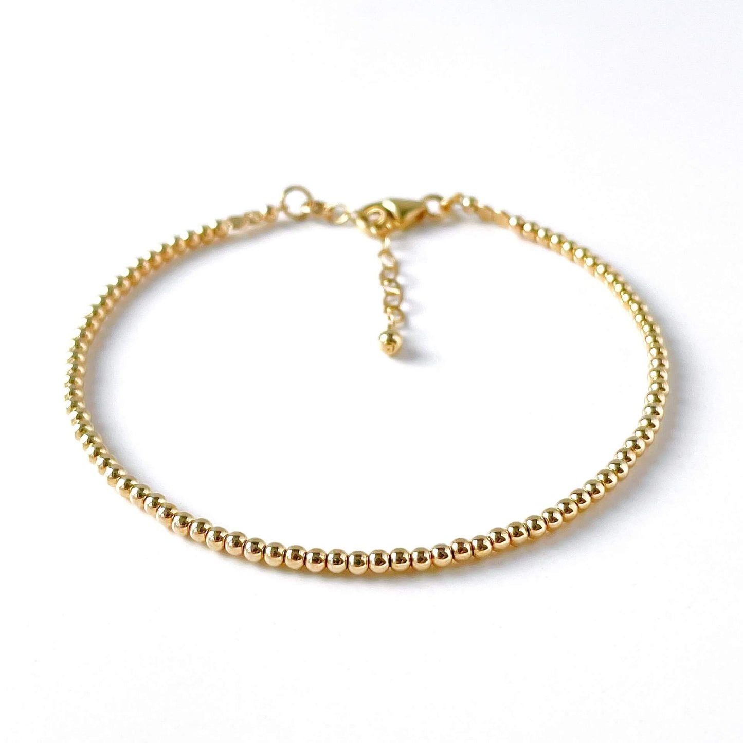 Gold beaded bracelet on a white background