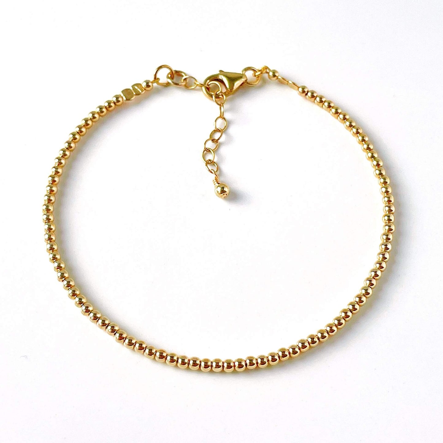 Gold bracelet with 2mm gold filled beads on a white background