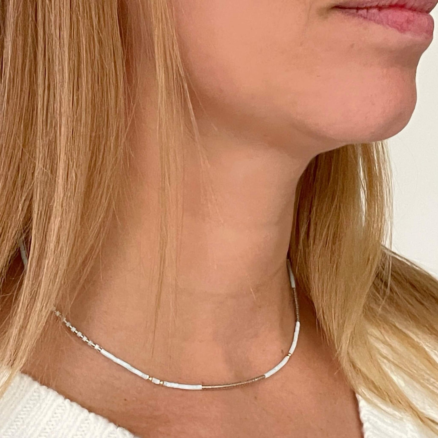 Dainty adjustable necklace with blue and gold beads worn on neckline