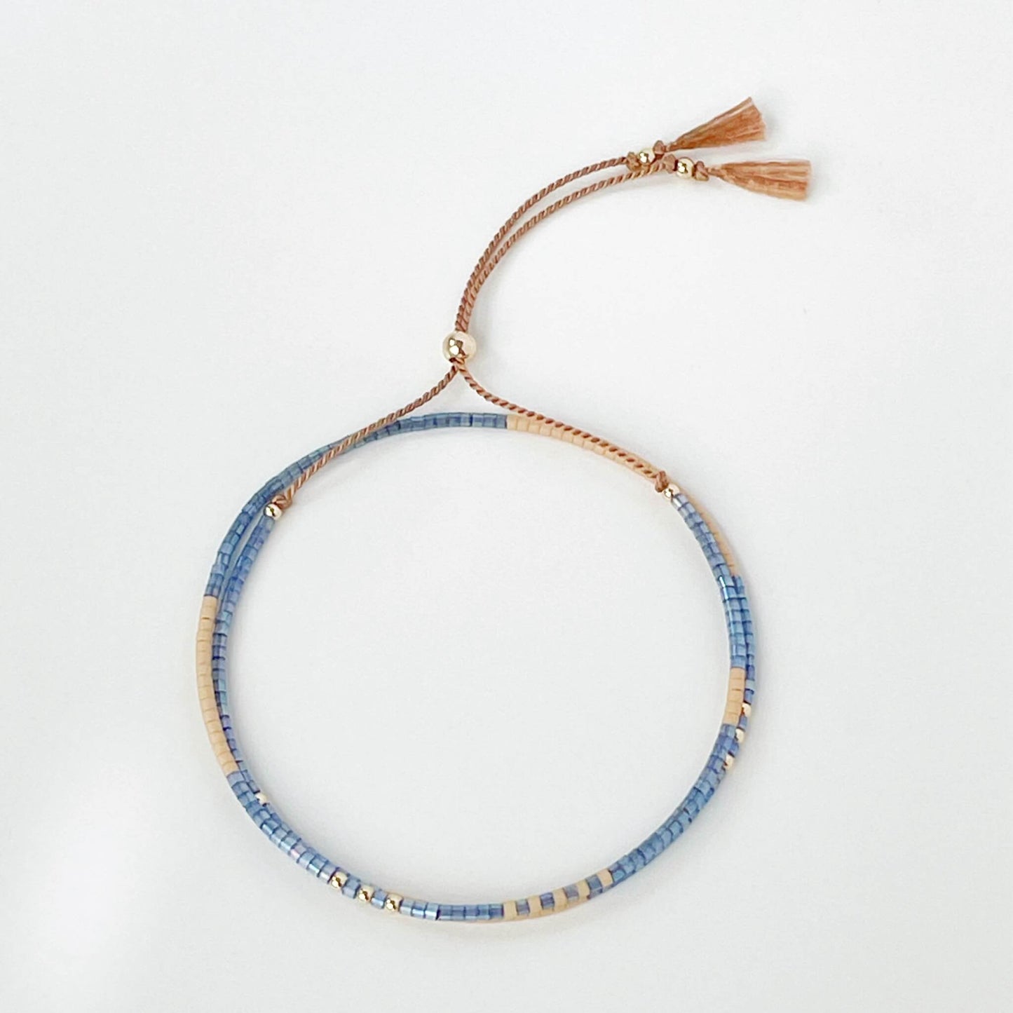 Lone Star double wrap bracelet with denim blue and beige Miyuki beads on a beige silk with tassel ends on a white background
