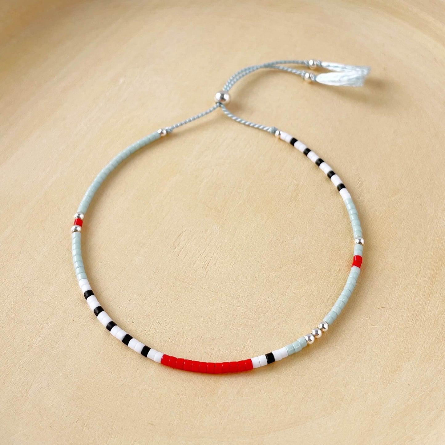 Necklace with red, black, and white beads on a beige background
