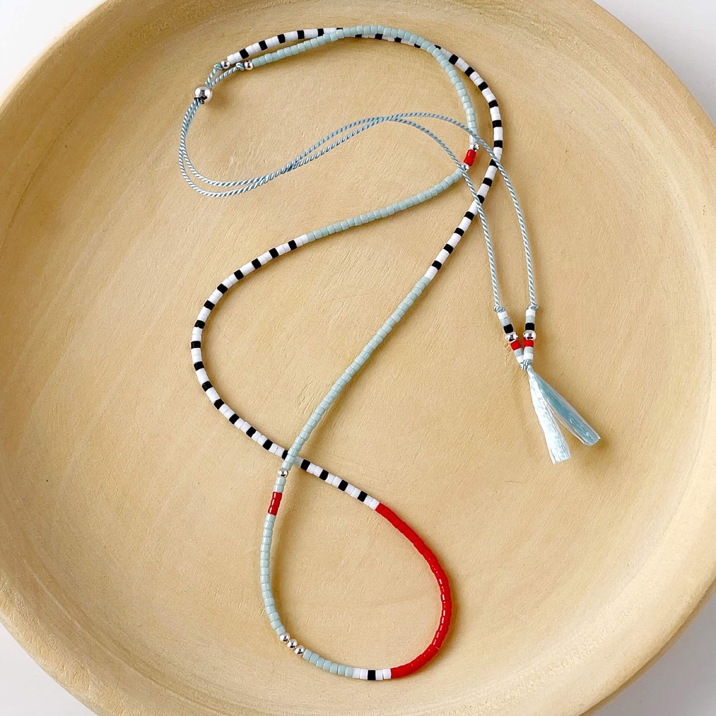 Necklace with red, black, and white pattern on a beige surface