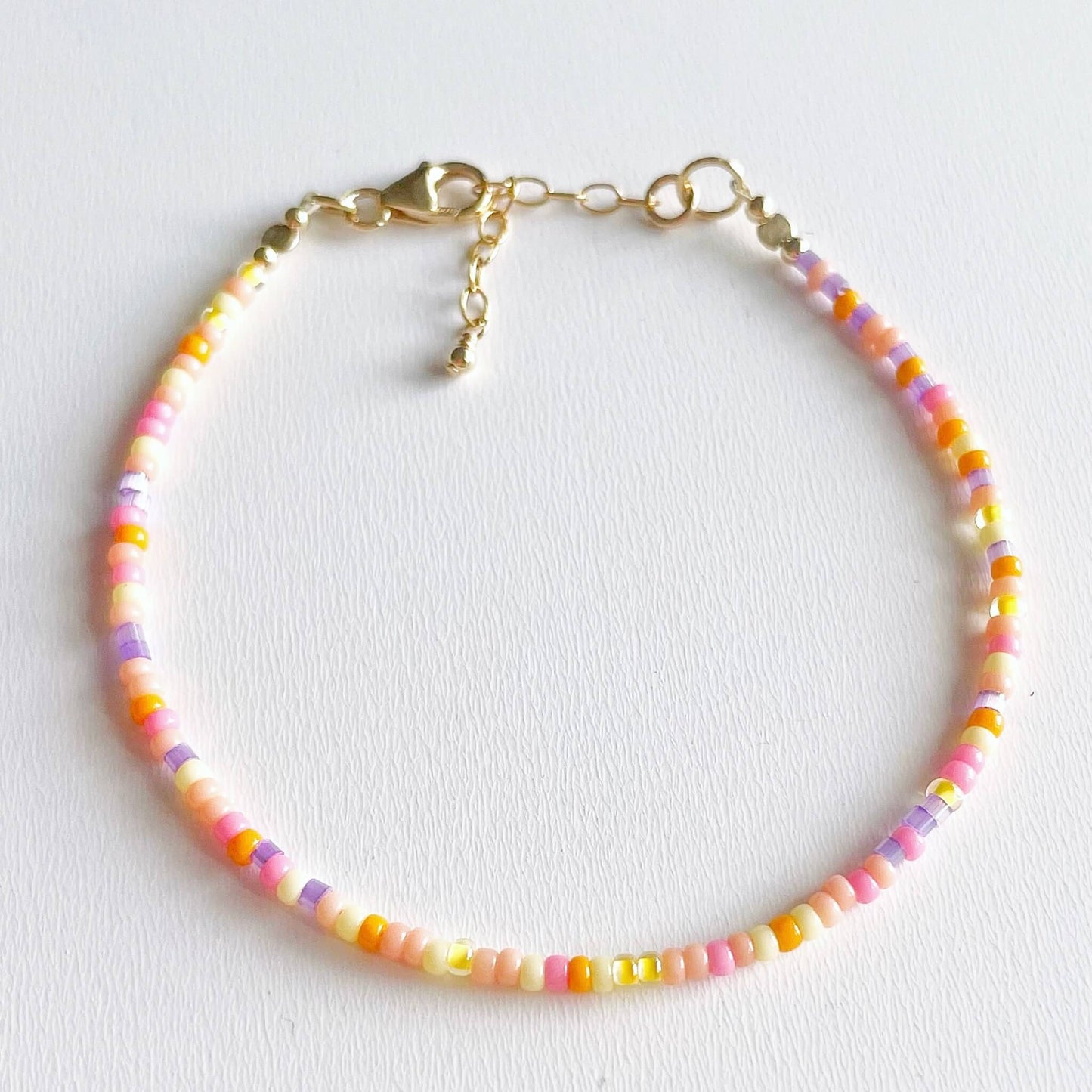 dainty beaded bracelet with pink, yellow, orange and lilac glass beads and gold fill accents