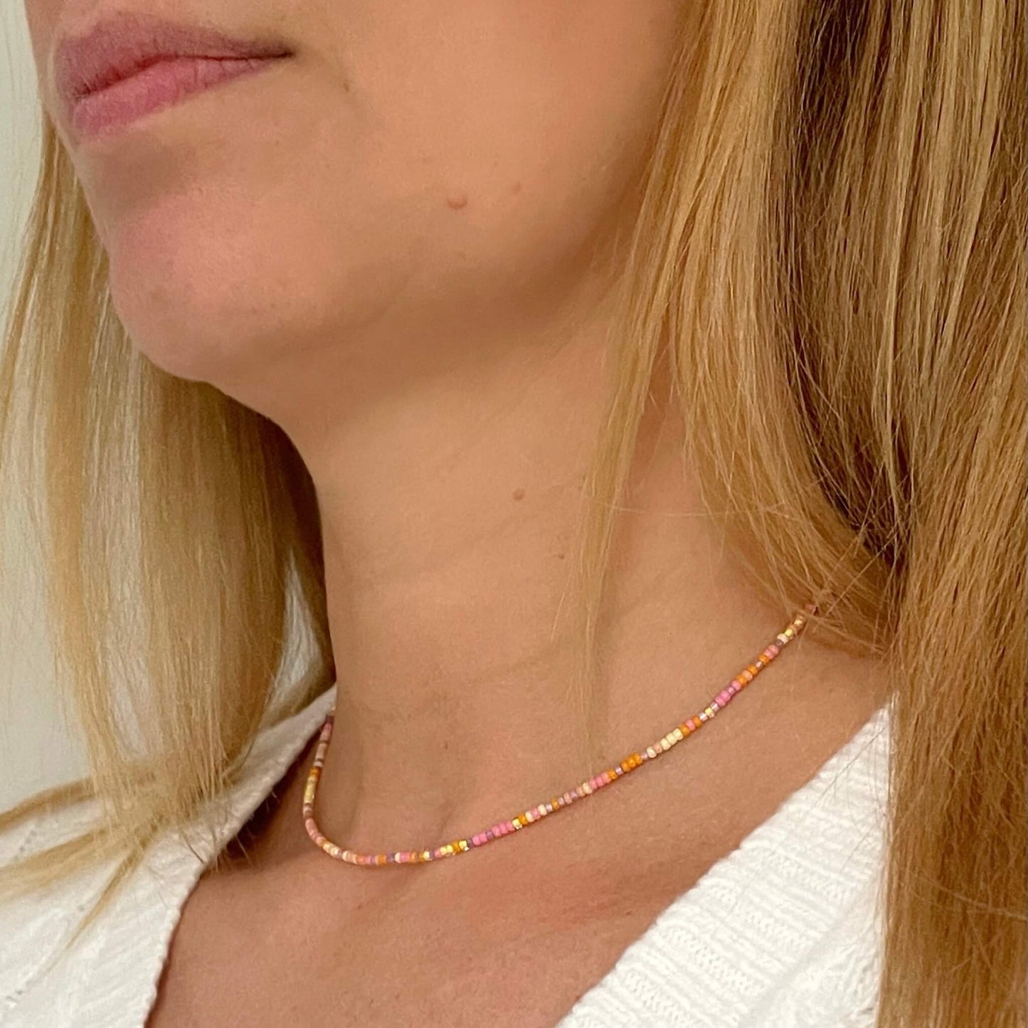 tiny beaded necklace with orange, pink, yellow and purple Miyuki glass beads and gold fill accents seen worn on the neck