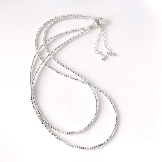 Dainty sterling silver bead necklace inspired with a lobster clasp and extension chain against a white background
