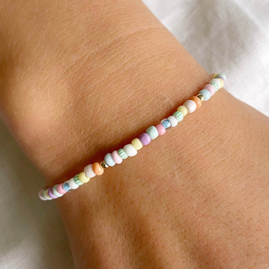 beaded bracelet with pastel glass beads in pink, blue, green, yellow, peach, white and lilac and gold fill accents shown worn on a wrist