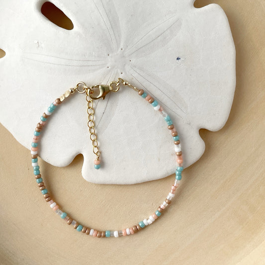 Beaded bracelet with gold clasp on a sand dollar