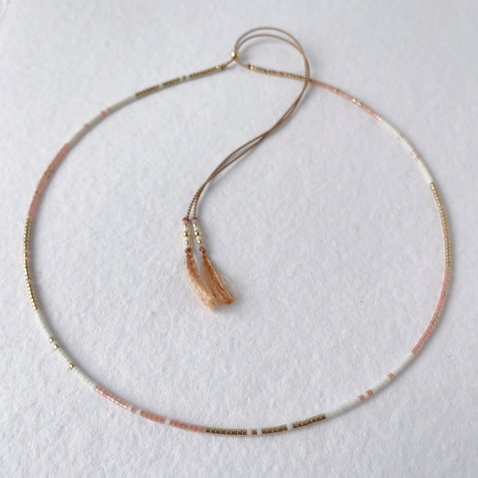 Delicate beaded necklace with peach, gold and white beads on adjustable silk cord