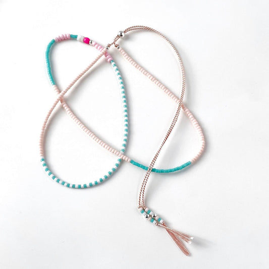 Pink and turquoise glass bead necklace with sterling silver accents on pale pink silk cord