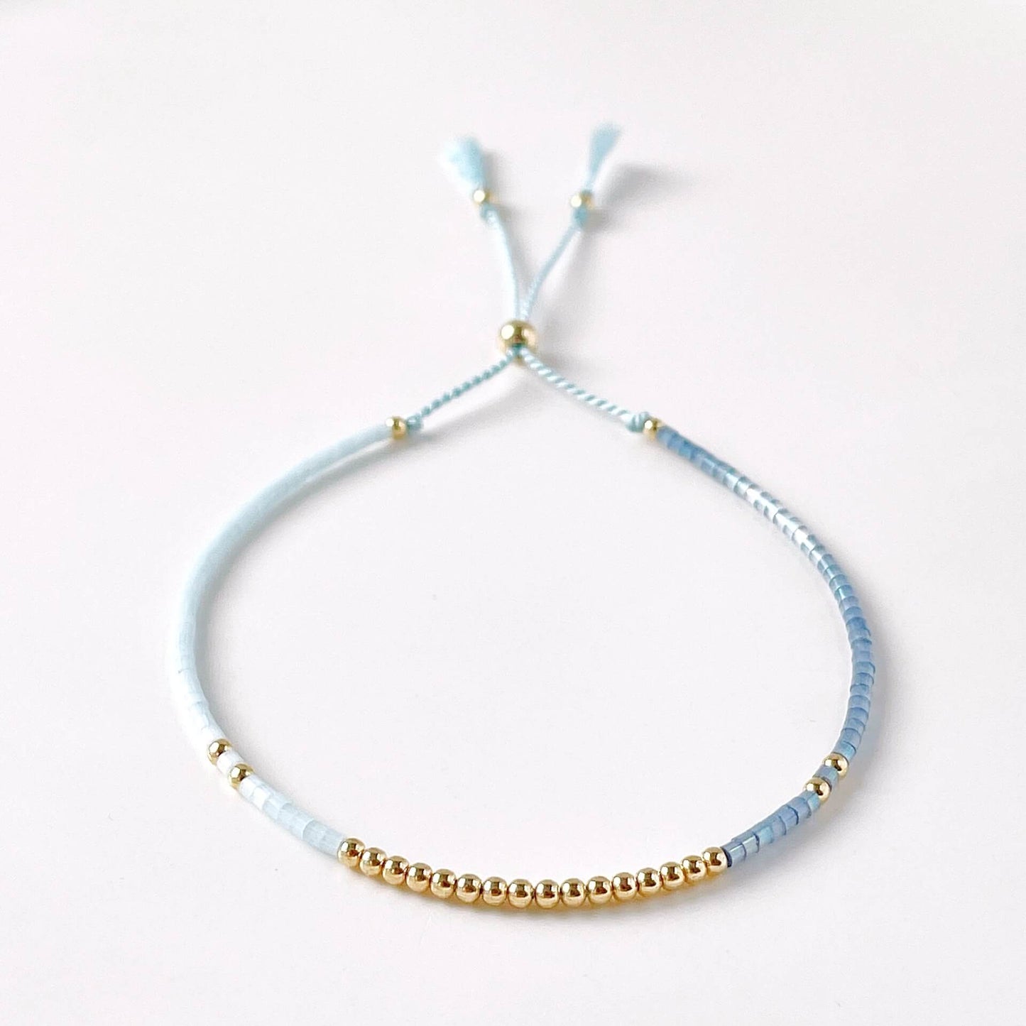 Bracelet with light blue and gold beads on a white background