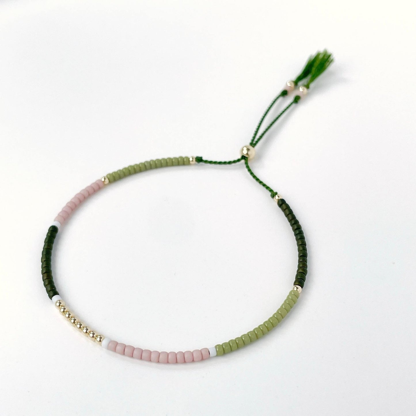 Dainty beaded bracelet with dusty pink, moss green, white, and dark olive Miyuki beads on olive silk cord with gold fill accents