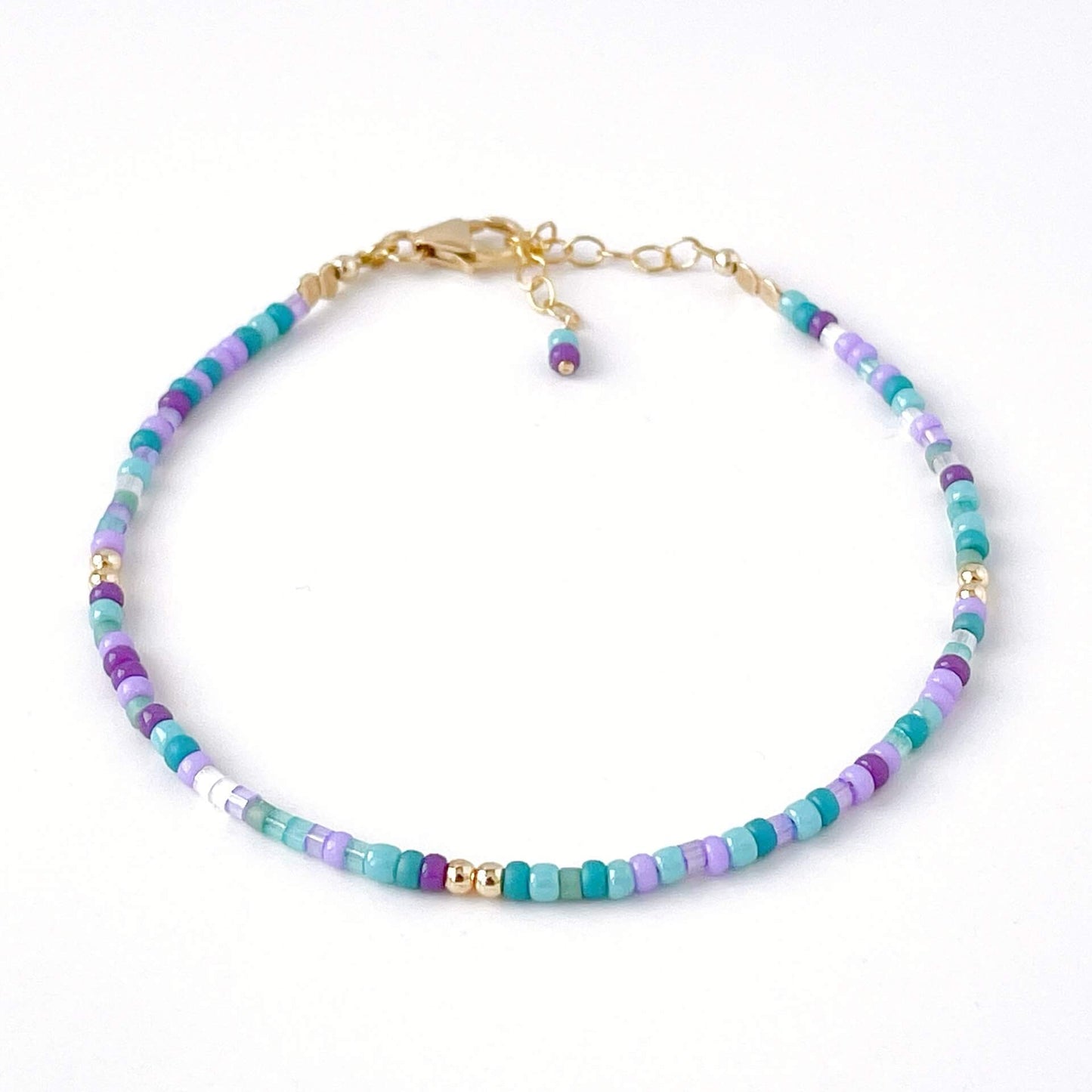 Multicolored beaded bracelet with gold accents on a white background