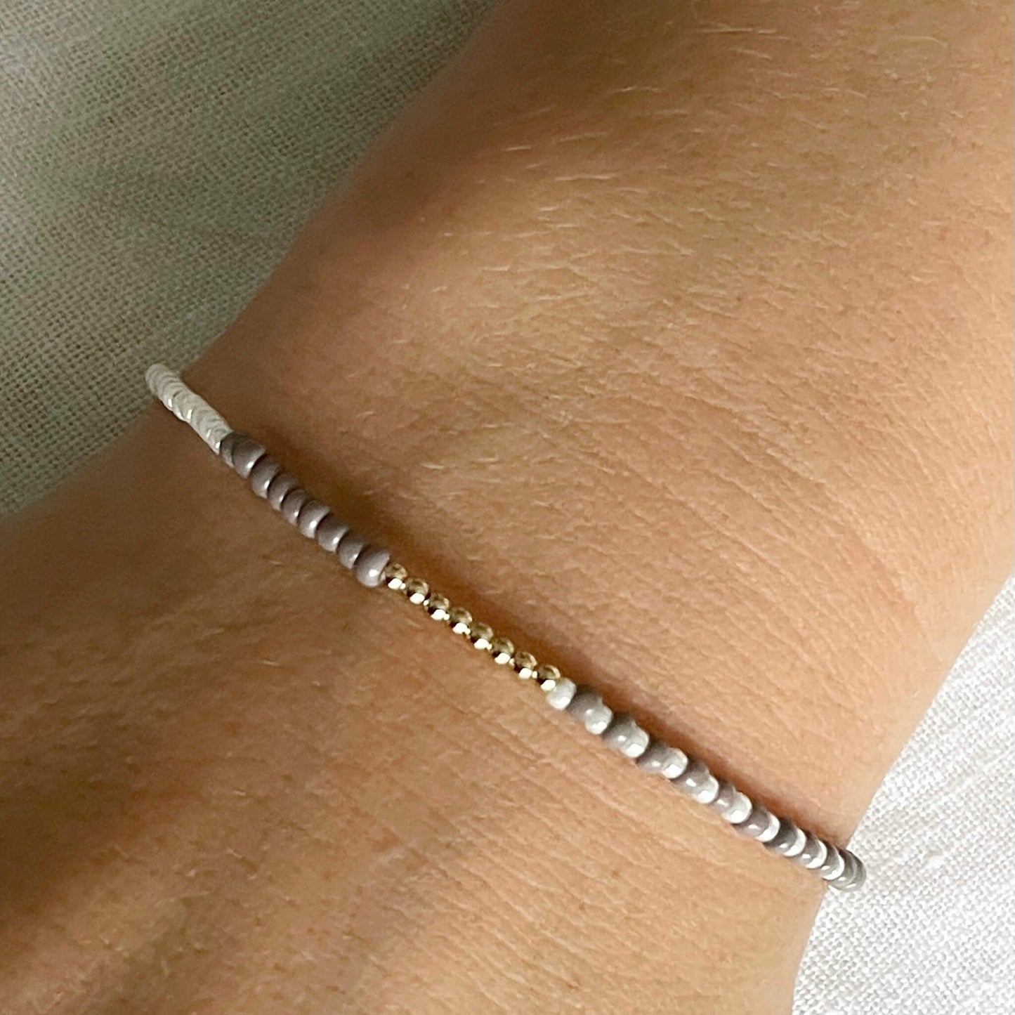 Beige & white glass beaded bracelet with gold fill accents worn on the wrist