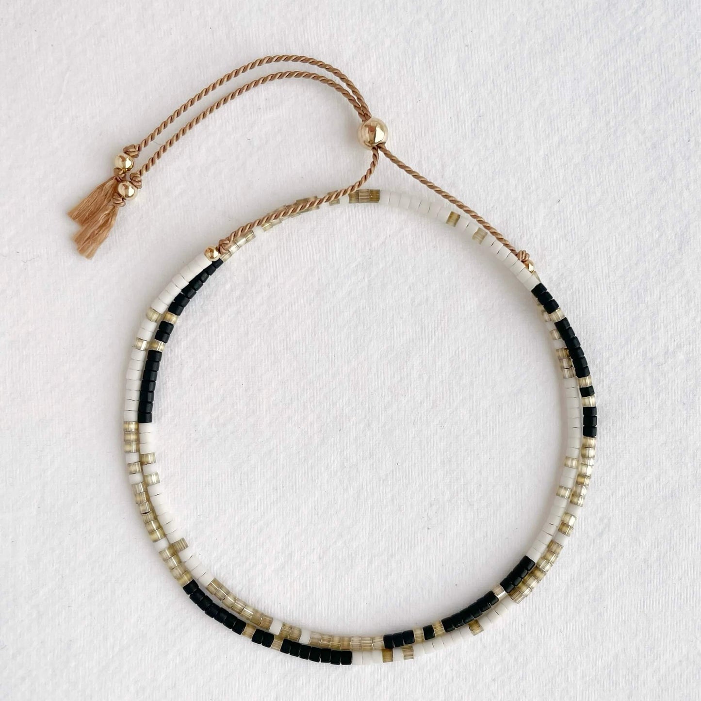 Double wrap silk bracelet with taupe, white, and black beads and gold accents