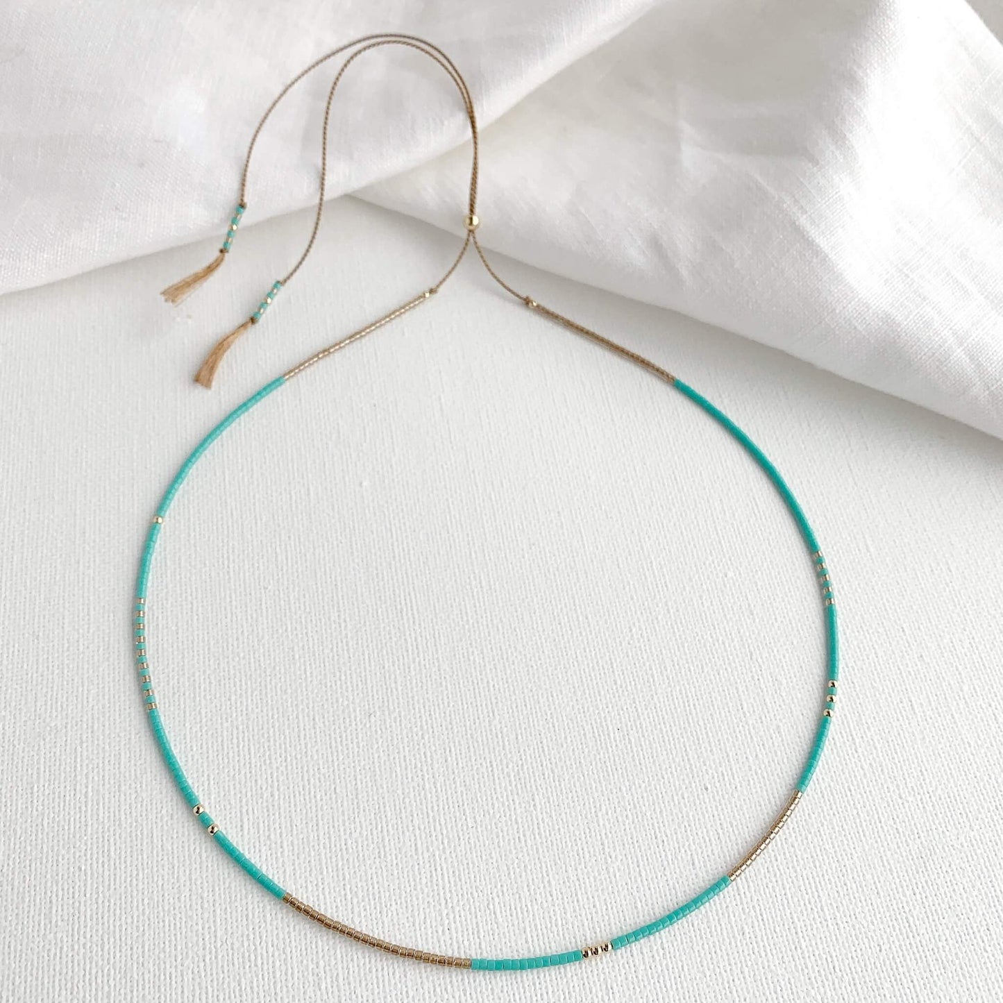 Turquoise and gold beaded necklace on beige silk cord with adjustable clasp
