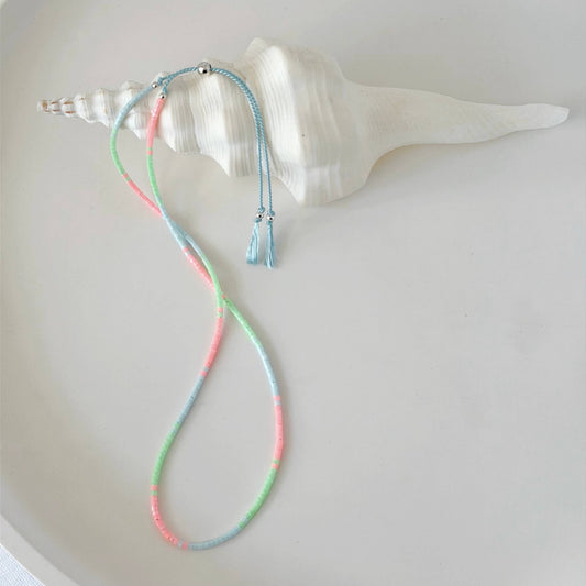 Dainty double wrap green, pink and pale blue glass bead bracelet with sterling silver sliding clasp on a neutral surface with white shell