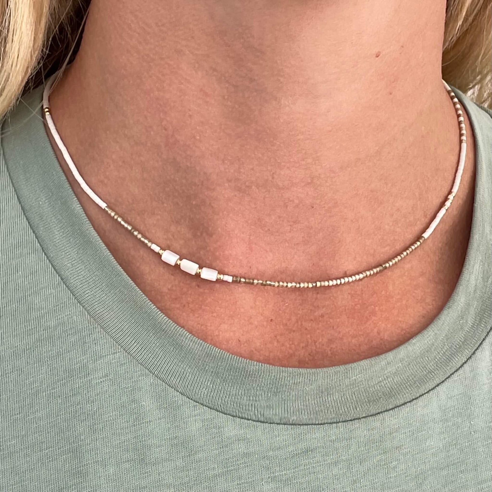 asymmetrical beaded beige white gold and other of pearl necklace shown on a neck
