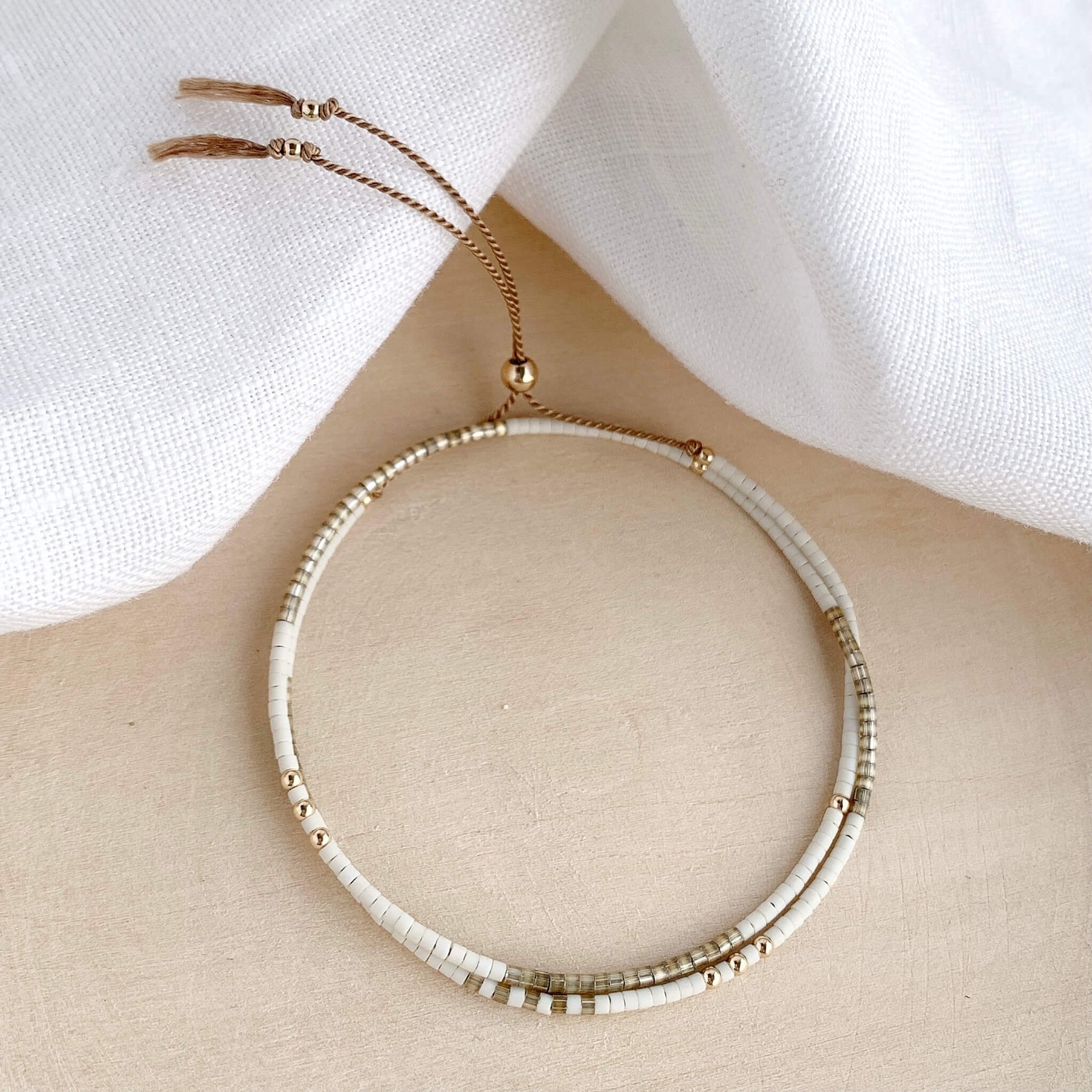 dainty beaded silk bracelet in beige and white with a gold clasp