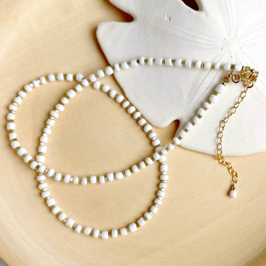 Beige and white beaded necklace with a gold lobster clasp and extension chain.