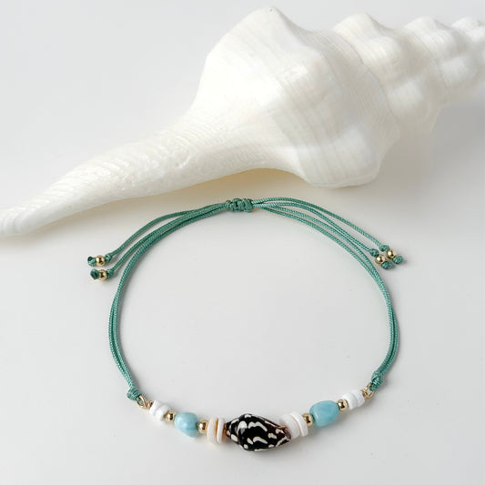 nylon teal cord bracelet with shell and gold beads on white background with white shell