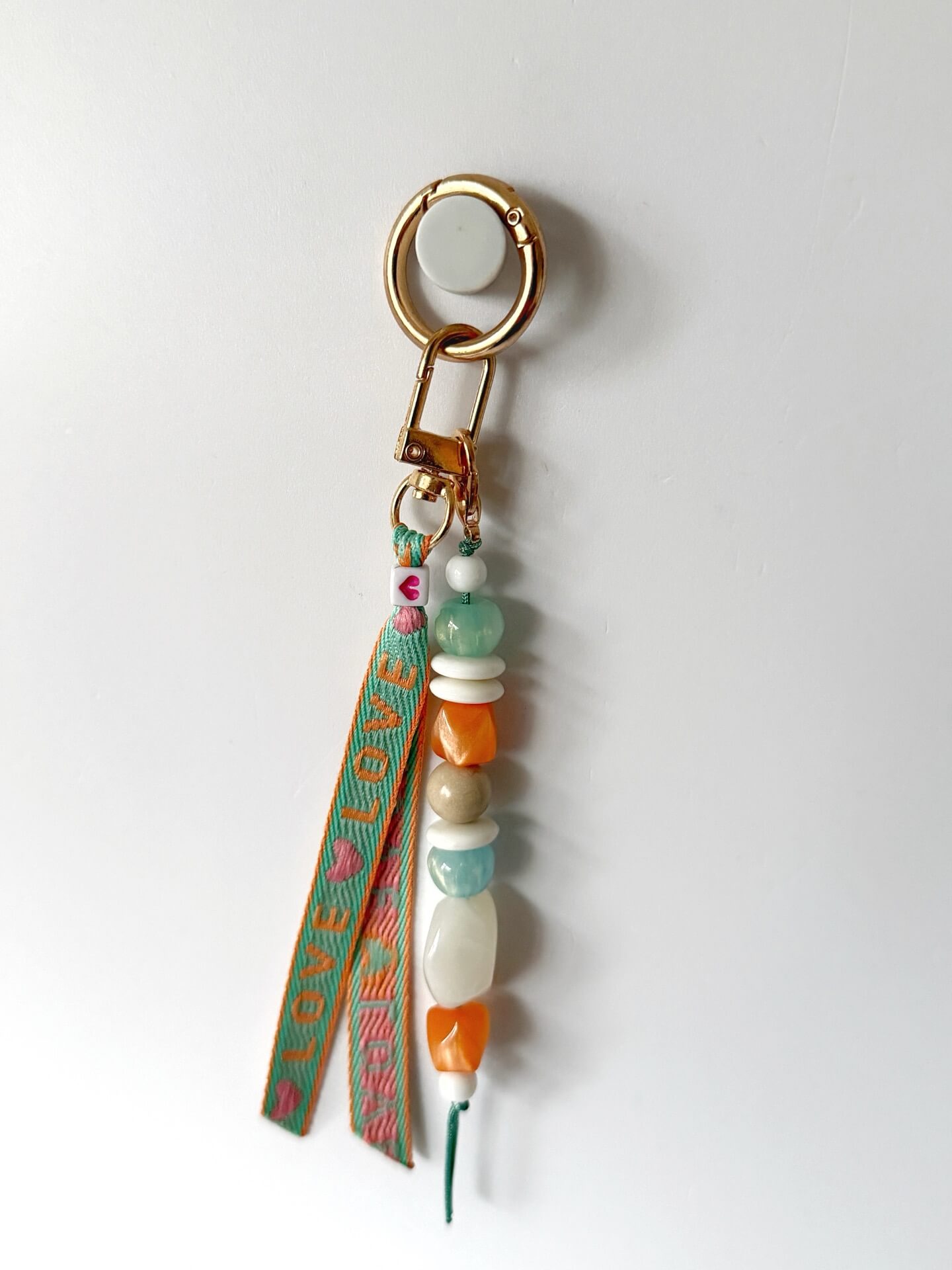 beaded ribbon bag charm with a love ribbon in mint and orange and aqua, white and orange chunky resin beaded on a gold clasp