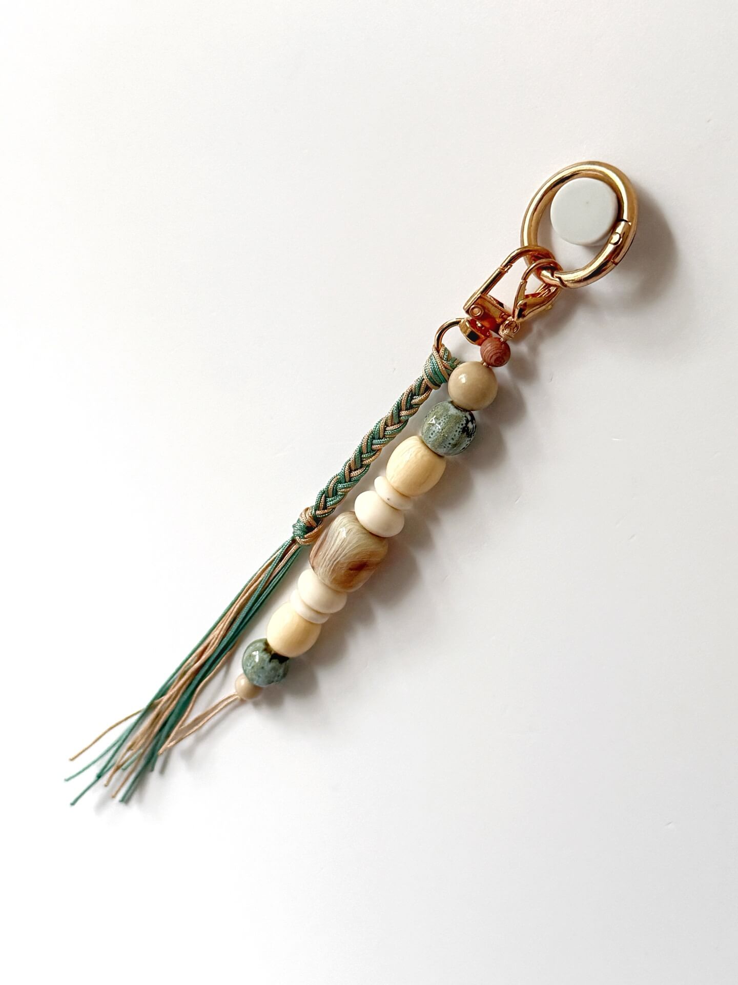 golden carabiner bag charm with blue and beige chunky beads with a braided nylon cord tassel in aqua and beige 