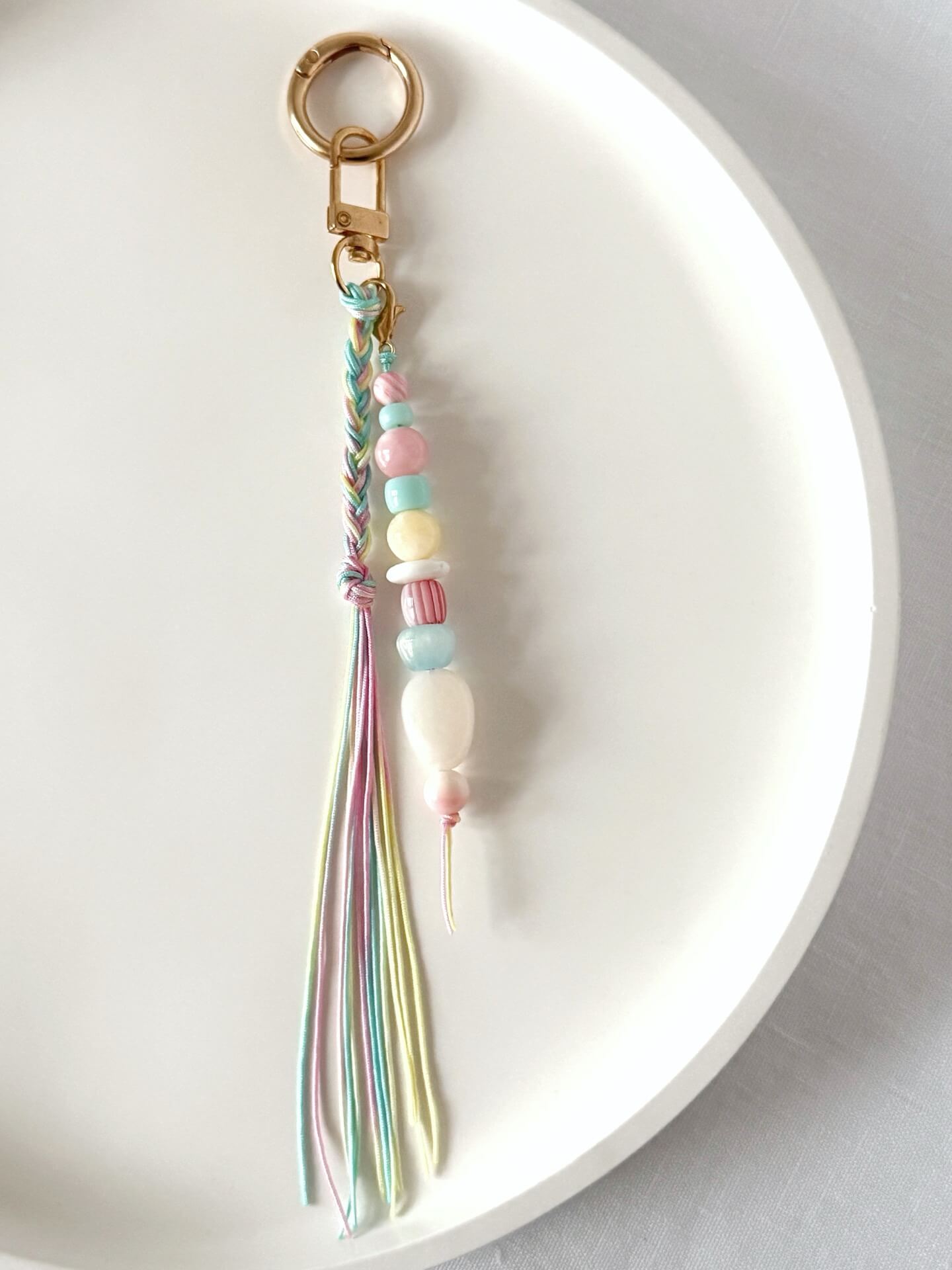 pastel chunky bead bag charm in pink, blue, lemon and white with a braided tassel in nylon cords in pink, blue and yellow
