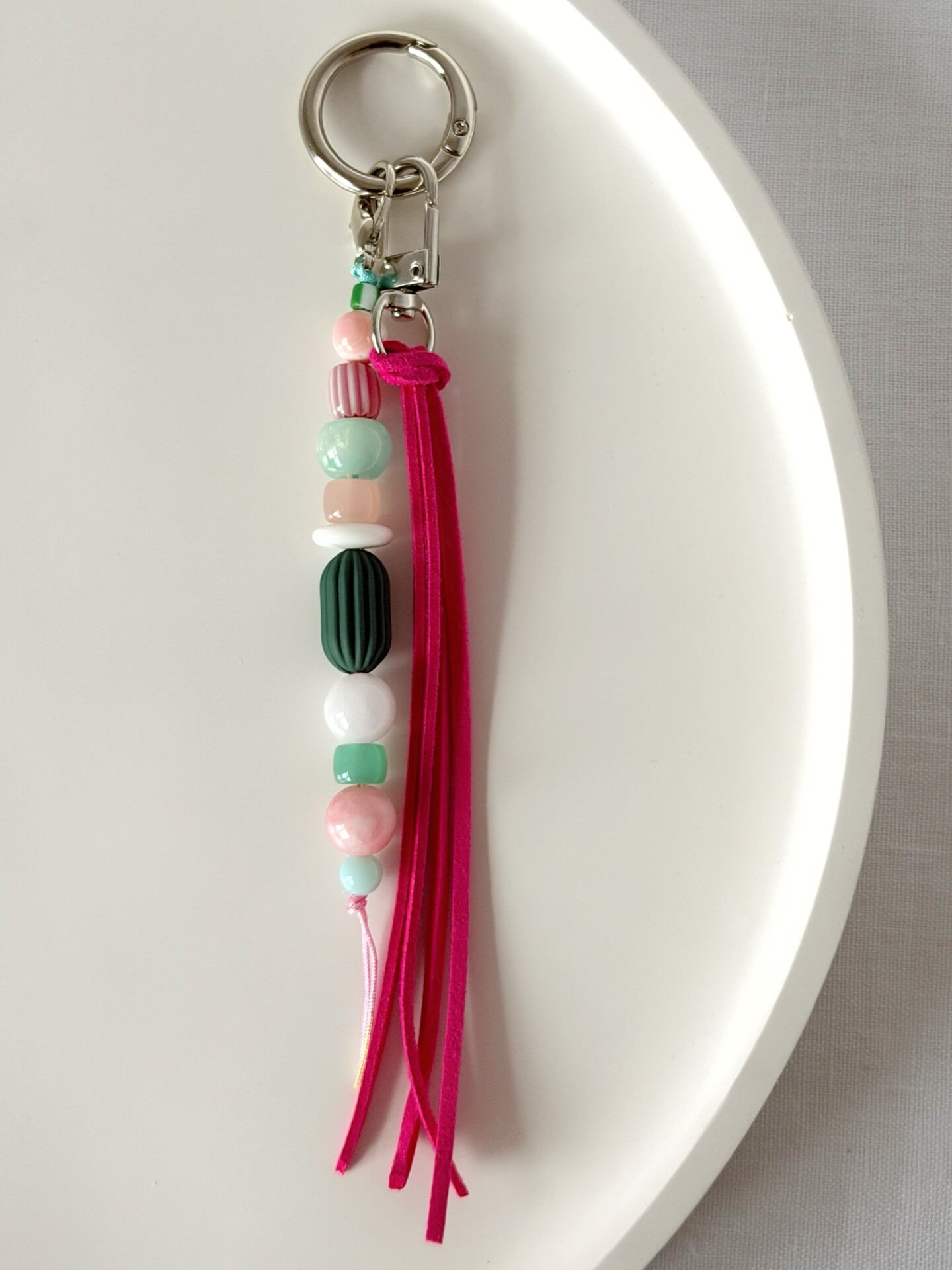 beaded bag charm with neon pink suedette tassel and chunky pink, green and white bead on a silver carabiner clasp