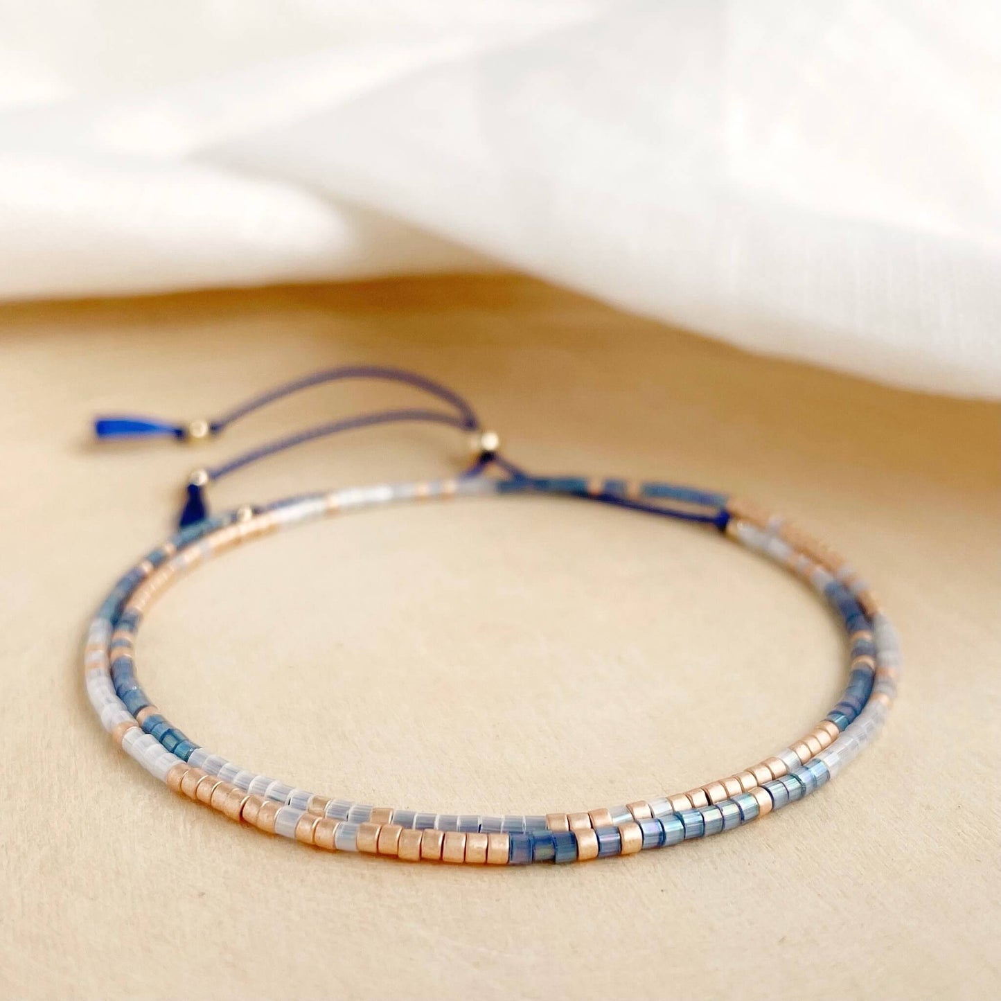 Double wrap friendship bracelet with blue, white and champagne beads and gold fill accents