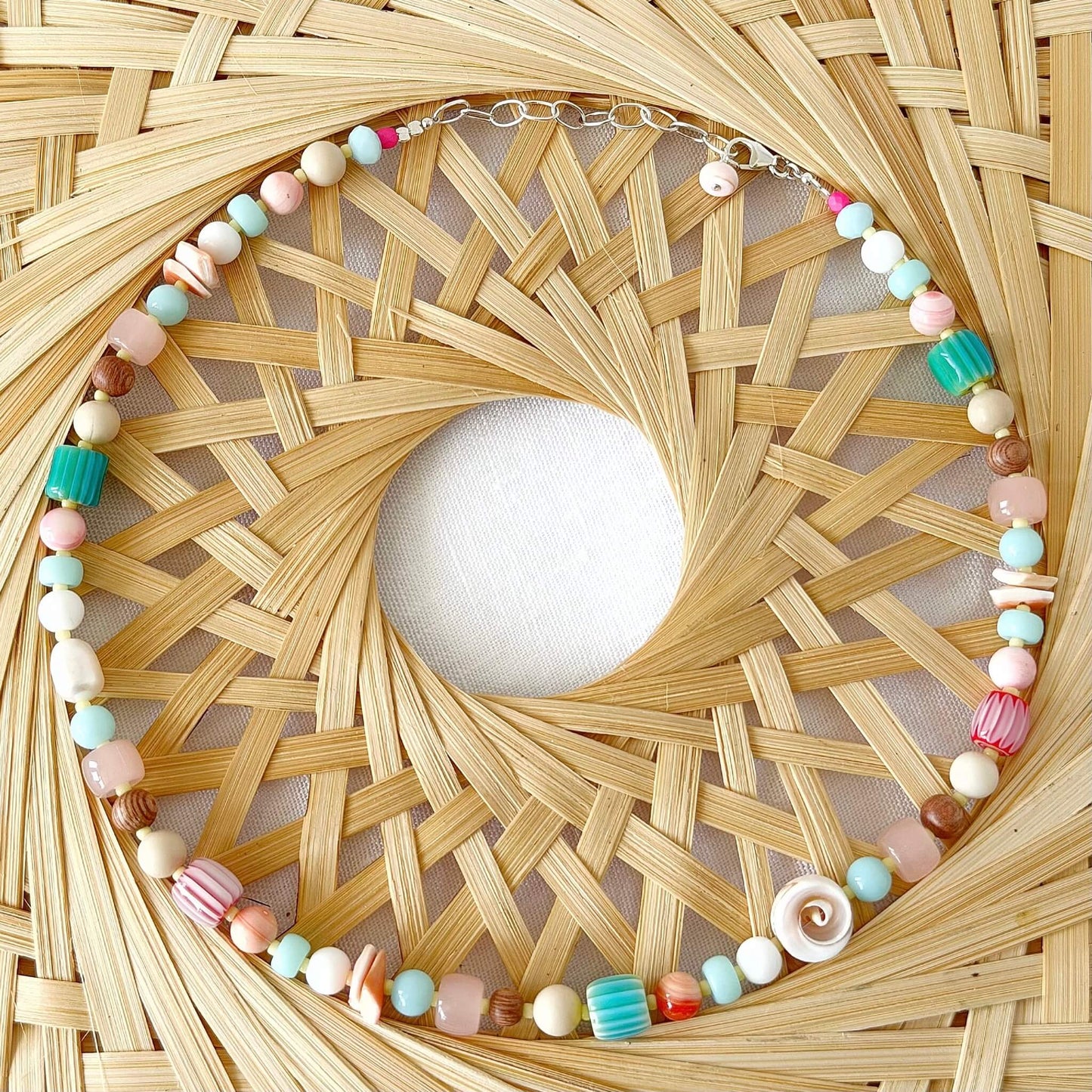 Necklace with colourful beads on a woven raffia surface