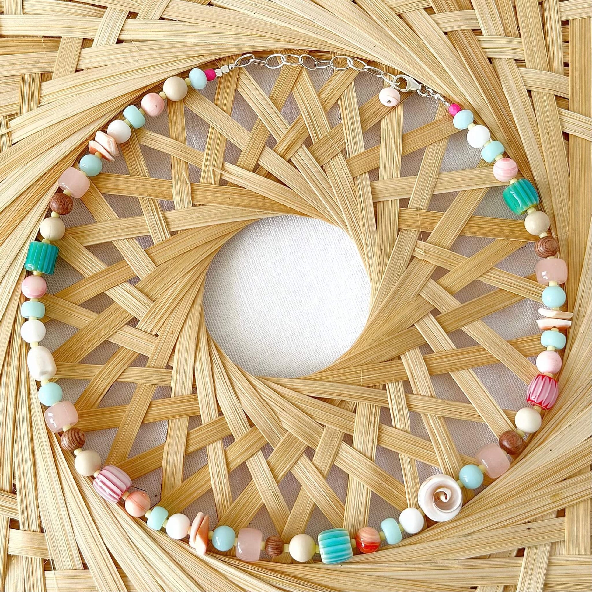 Necklace with colourful beads on a woven raffia surface
