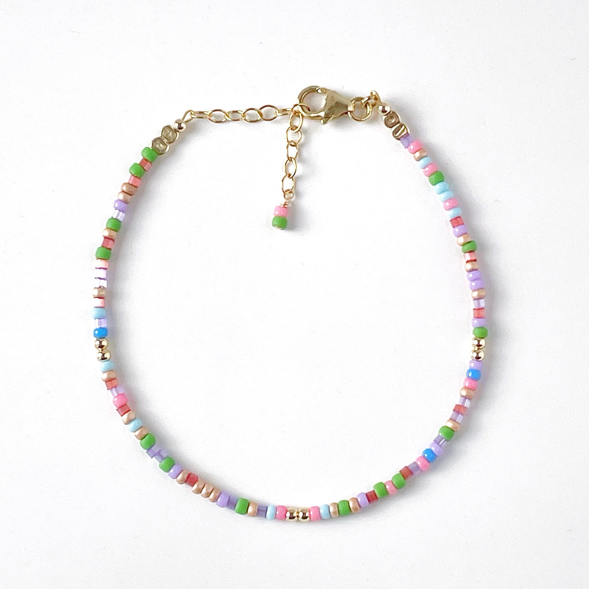 Dainty beaded bracelet with pink, blue, green, red, purple and lilac beads with gold fill clasp and extender chain