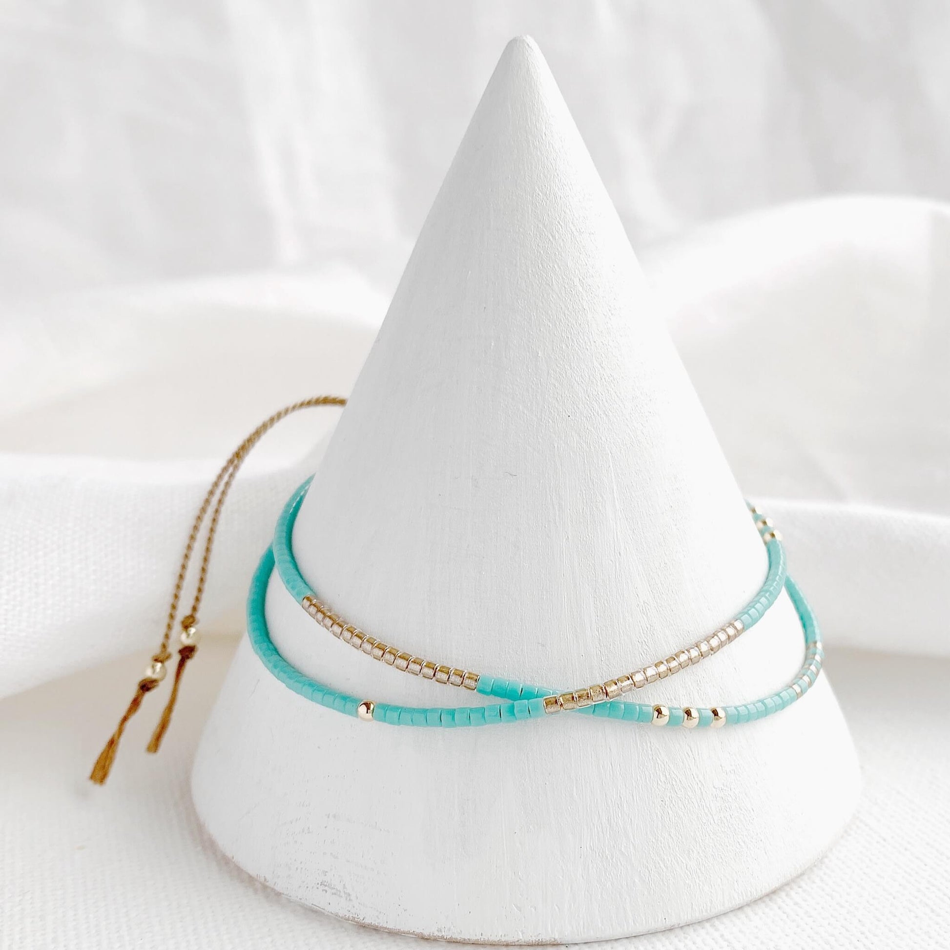 Double wrap bracelet with turquoise and gold beads and gold fill accents displayed on a cone