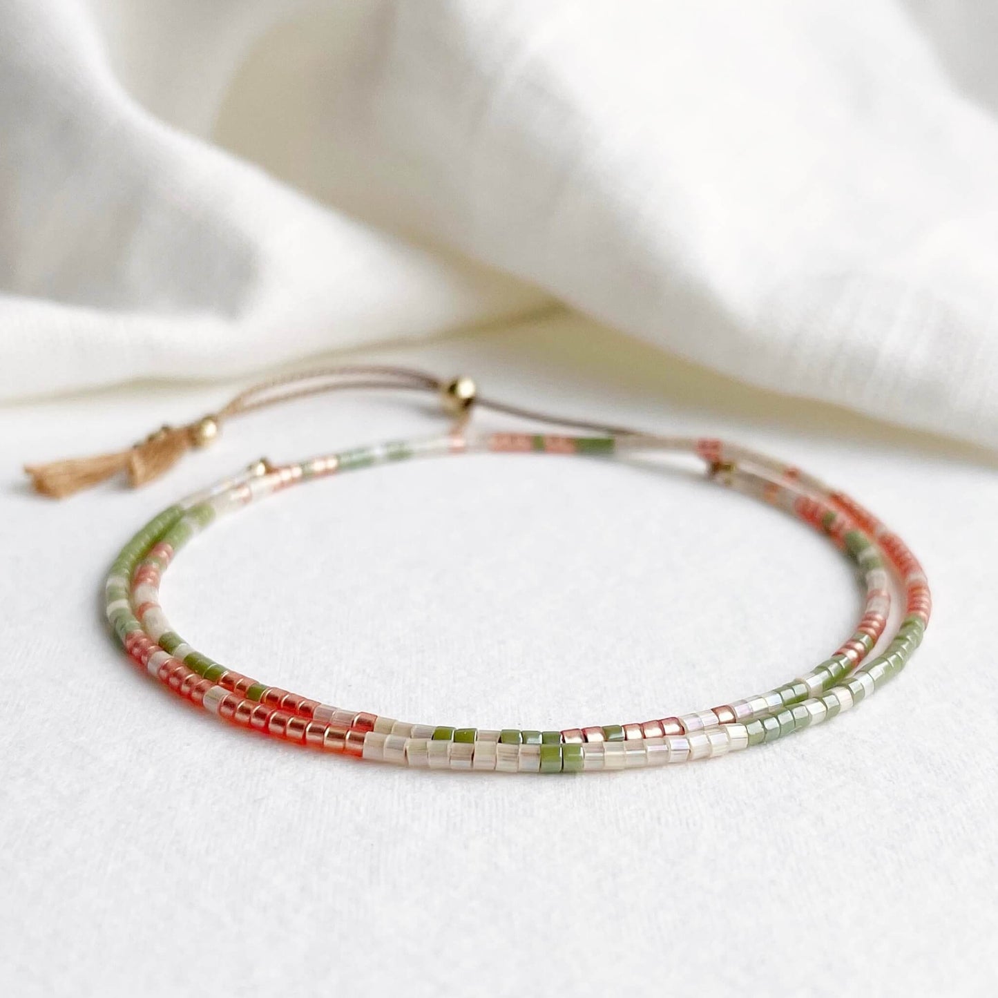 delicate friendship bracelet with green, orange and apricot glass beads and gold fill accents