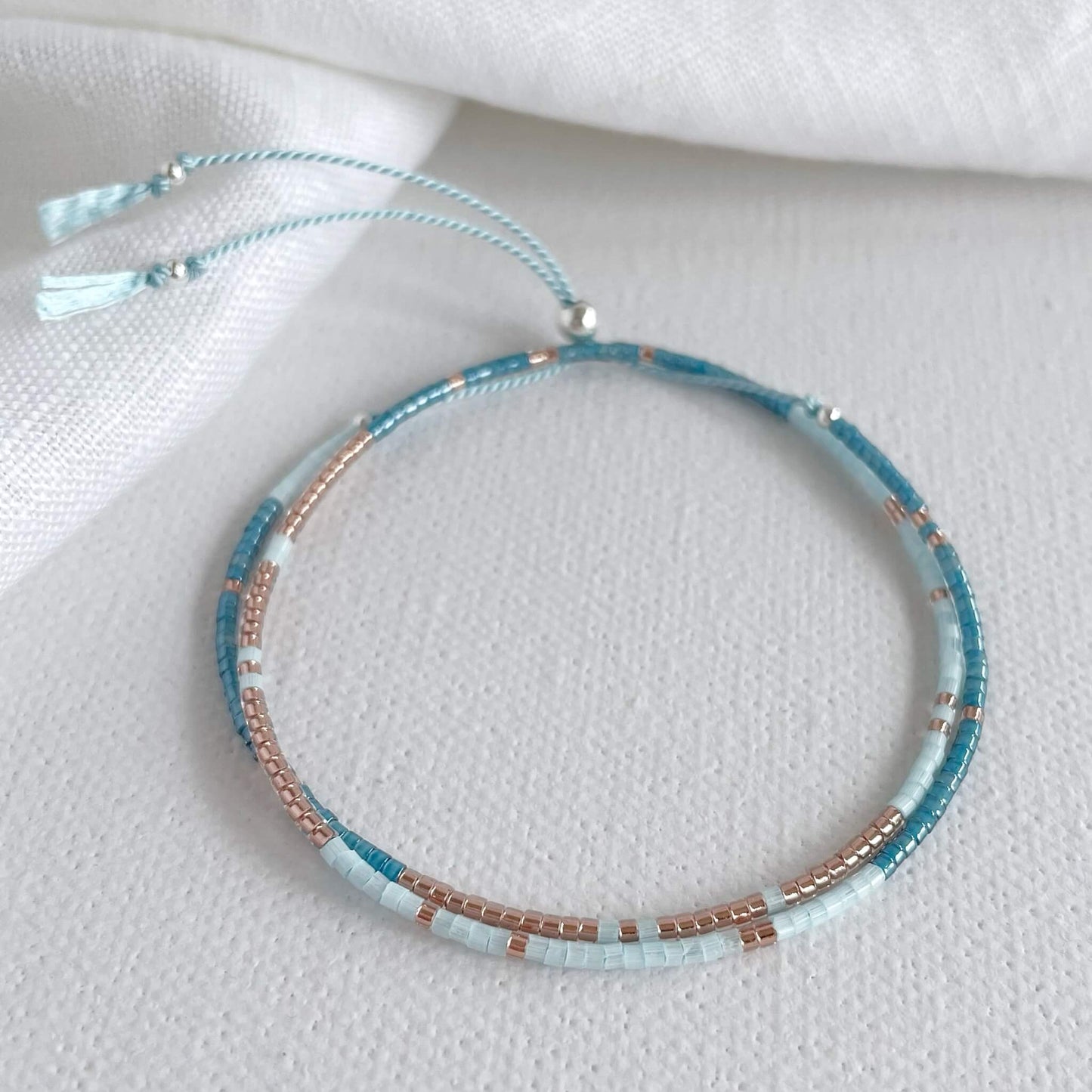 beaded double wrap bracelet with blue and copper glass beads and sterling silver accents on a pale blue silk cord