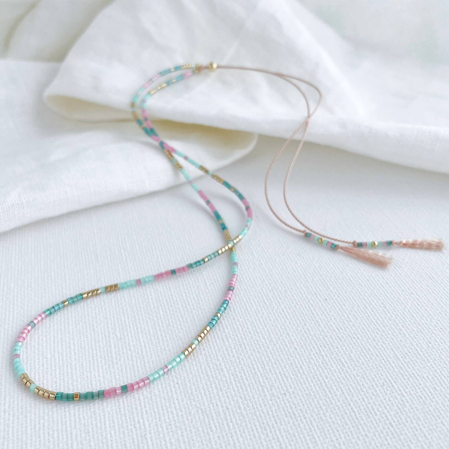 delicate beaded necklace with Pink, green and gold tiny glass beads on a pale pink silk cord with gold accents and adjustable length