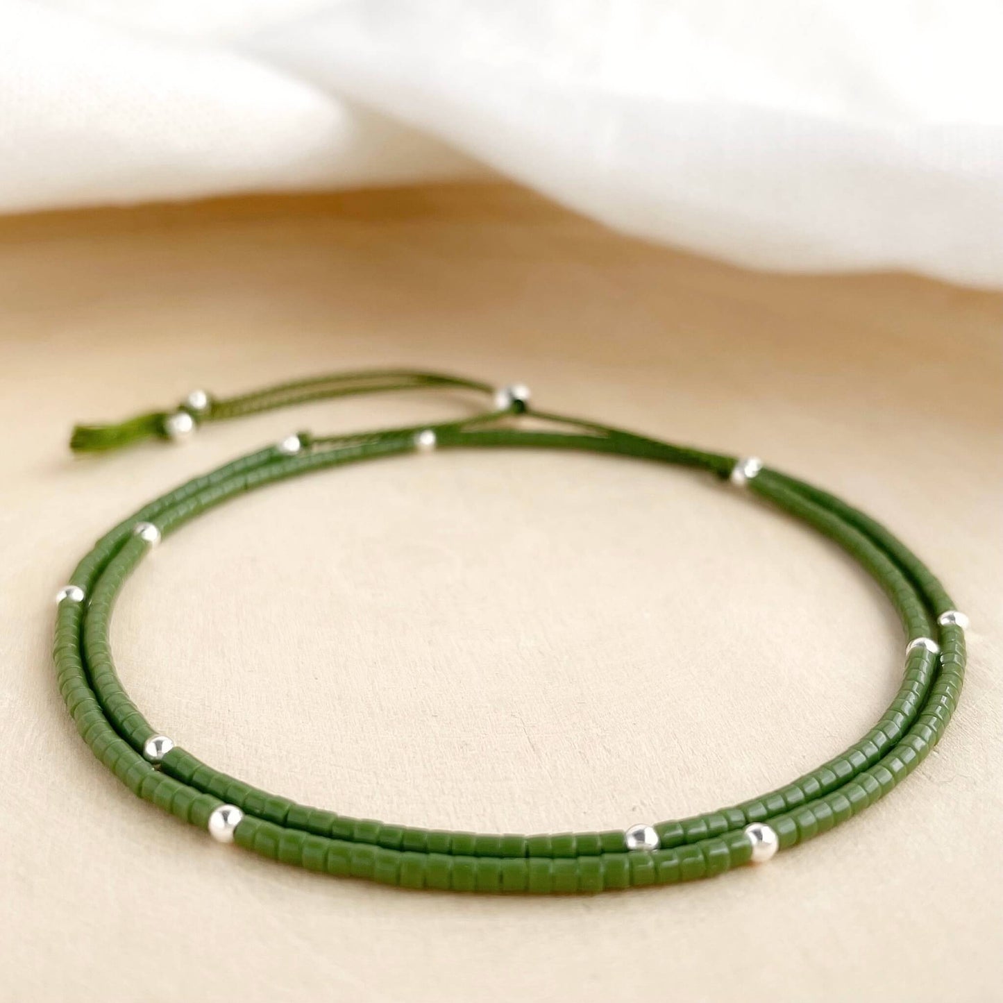 Fresh beaded double wrap bracelet in khaki green and silver with sterling silver accents on green silk cord