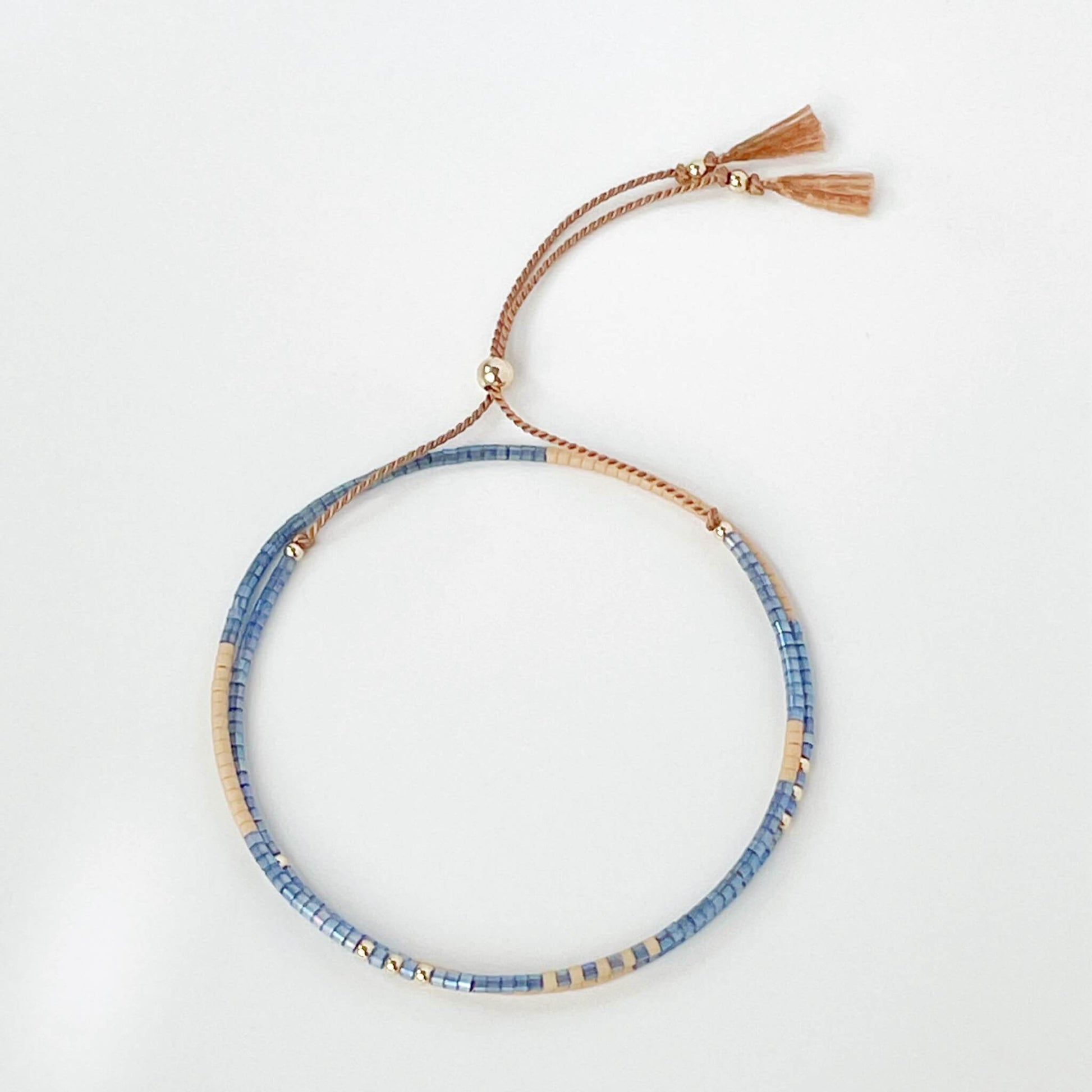 Lone Star double wrap bracelet with denim blue and beige Miyuki beads on a beige silk with tassel ends on a white background