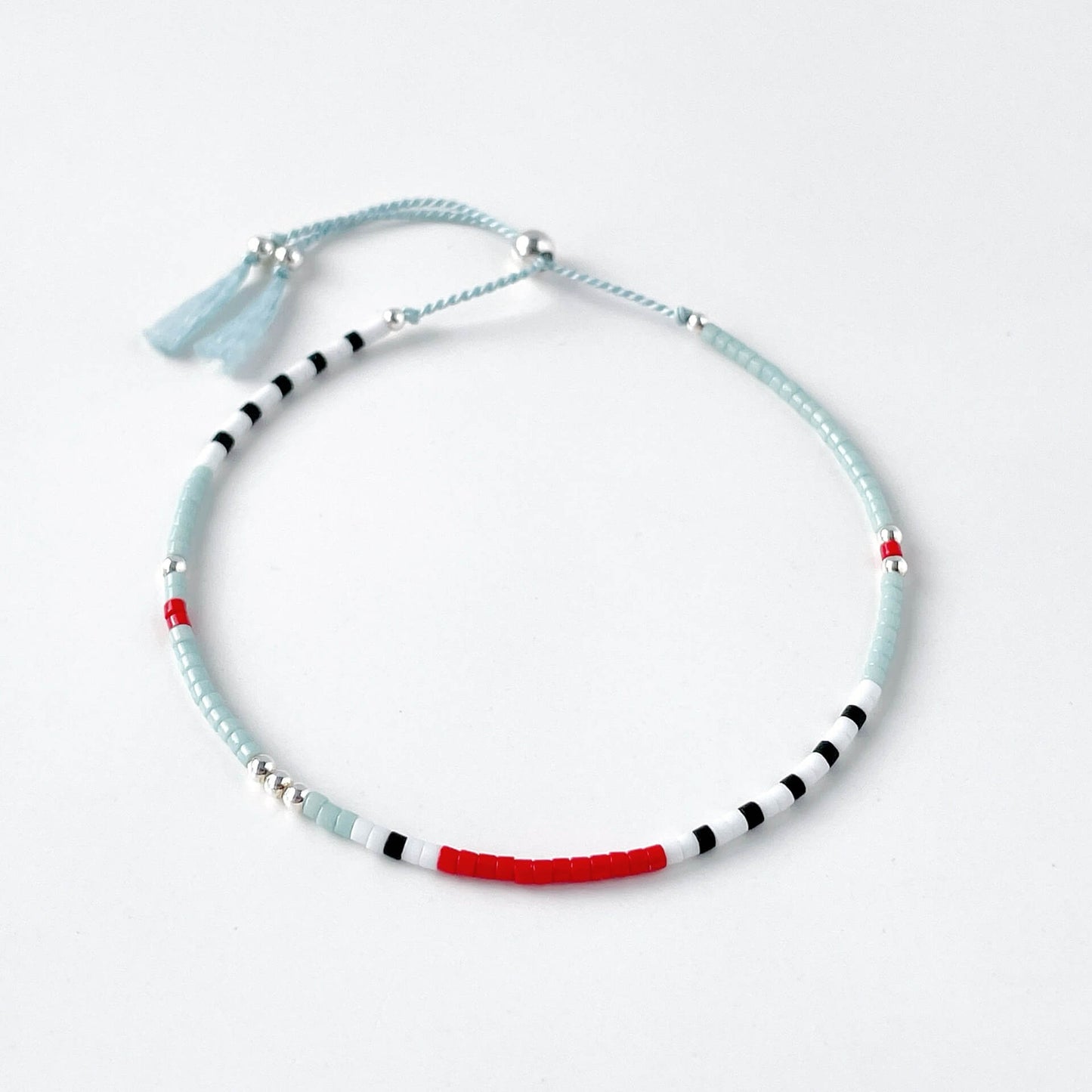 Seed bead bracelet with light blue, red, and black beads on a white background