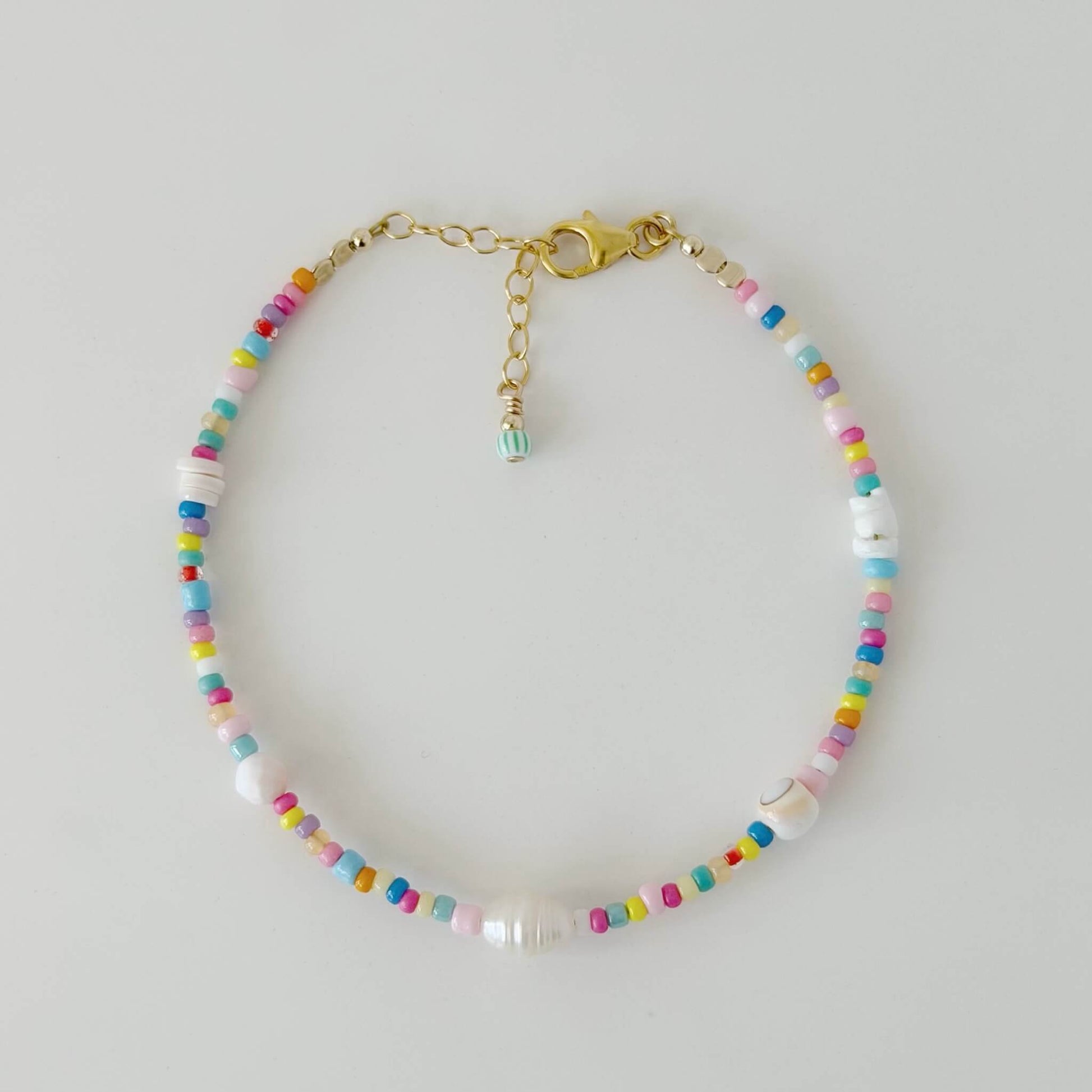 Multicolour glass bead and shell bracelet with gold fill clasp and extender chain on a white flat lay surface