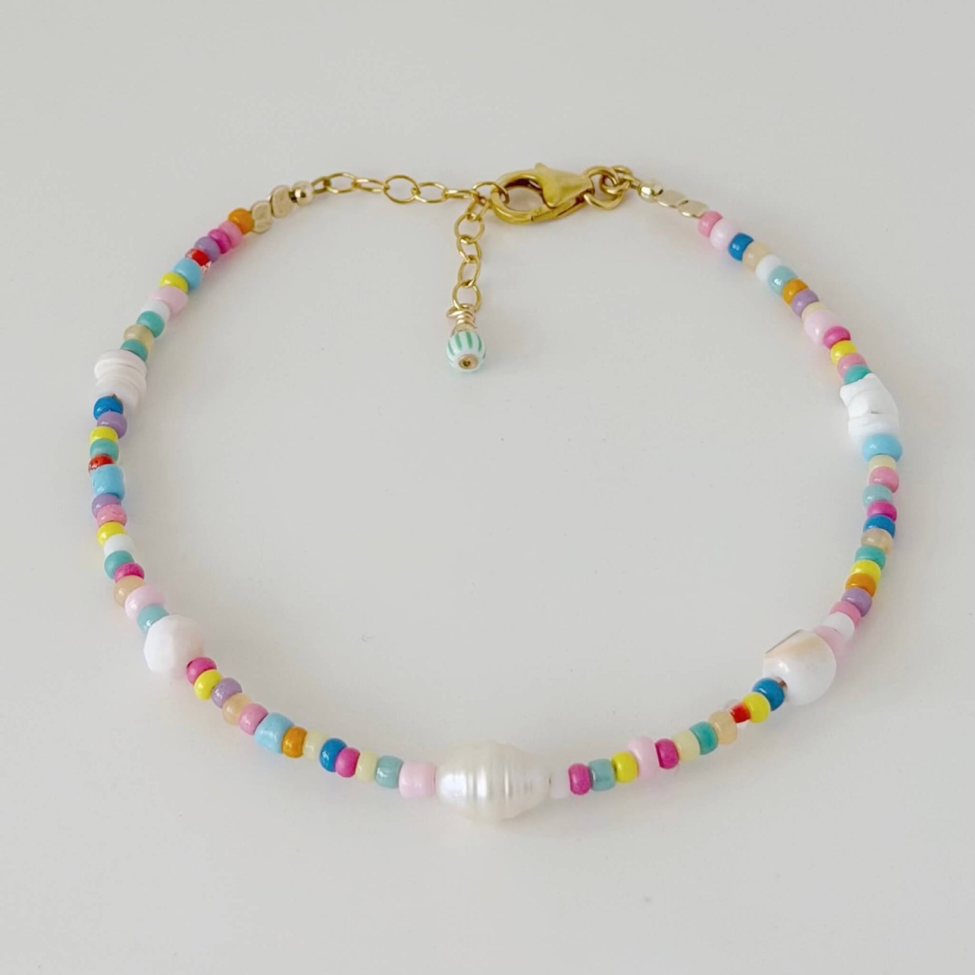 Colourful glass bead and shell bracelet with gold fill clasp and extender chain on a white flat lay surface