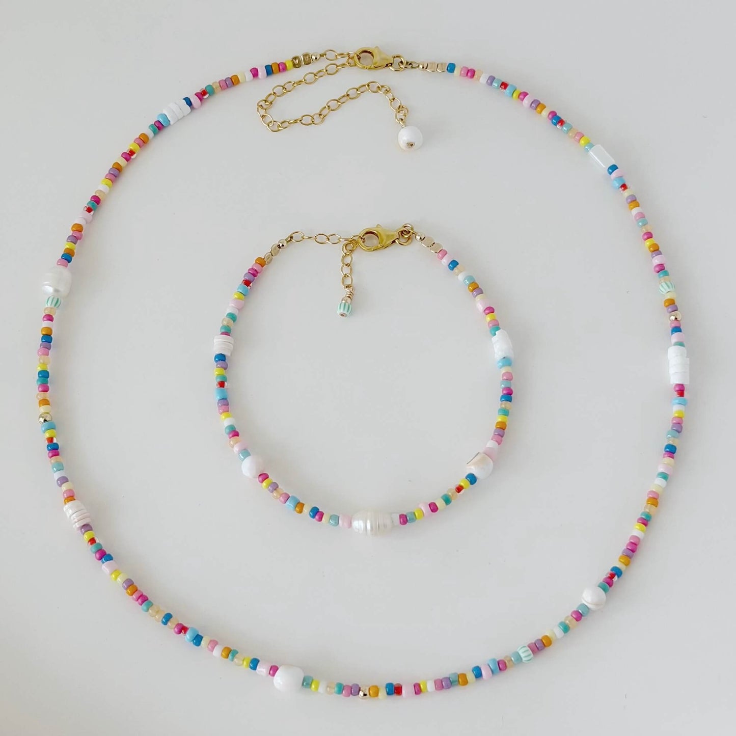 Colorful beaded necklace and bracelet set on a light gray background