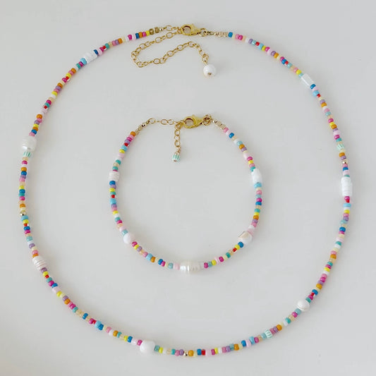 Colorful beaded necklace and bracelet set on a light gray background