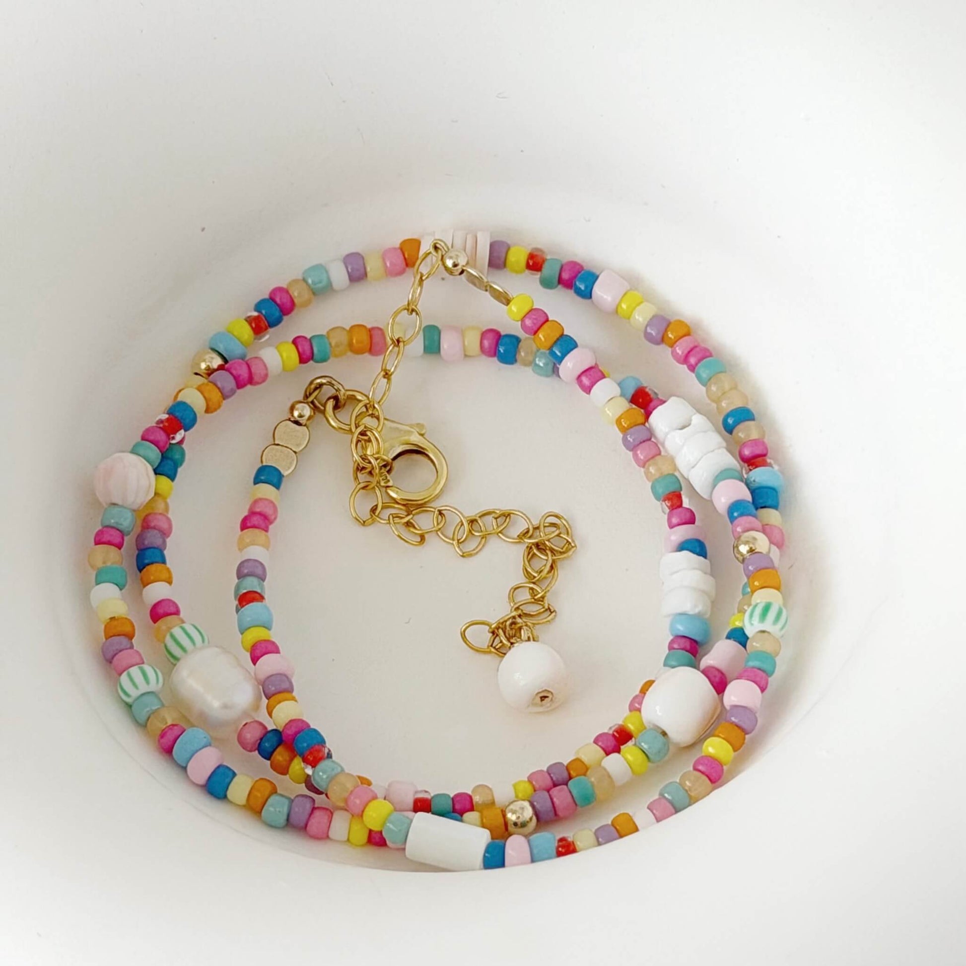 Colorful beaded necklace with gold chain on a white background