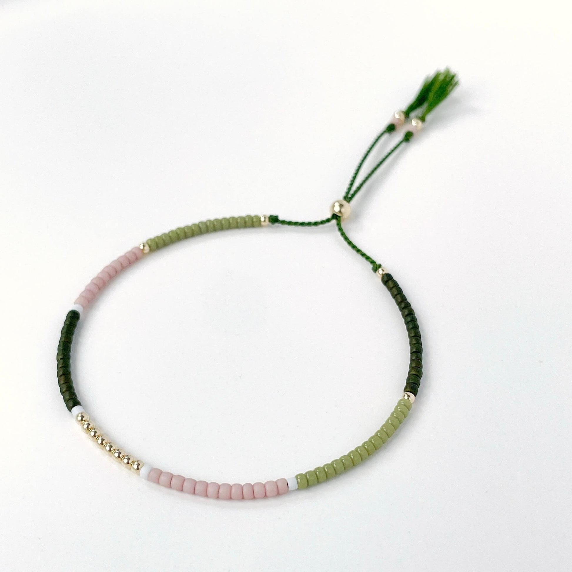Dainty beaded bracelet with dusty pink, moss green, white, and dark olive Miyuki beads on olive silk cord with gold fill accents