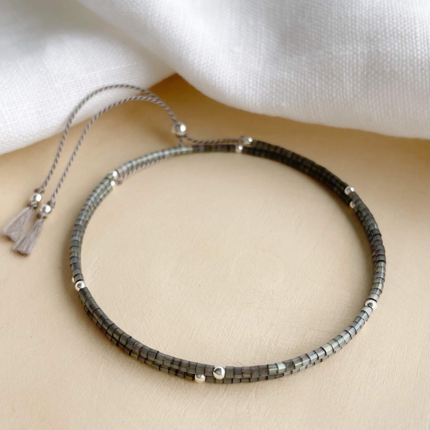 Sparkling double wrap bracelet with grey glass beads and sterling silver accents on wooden background