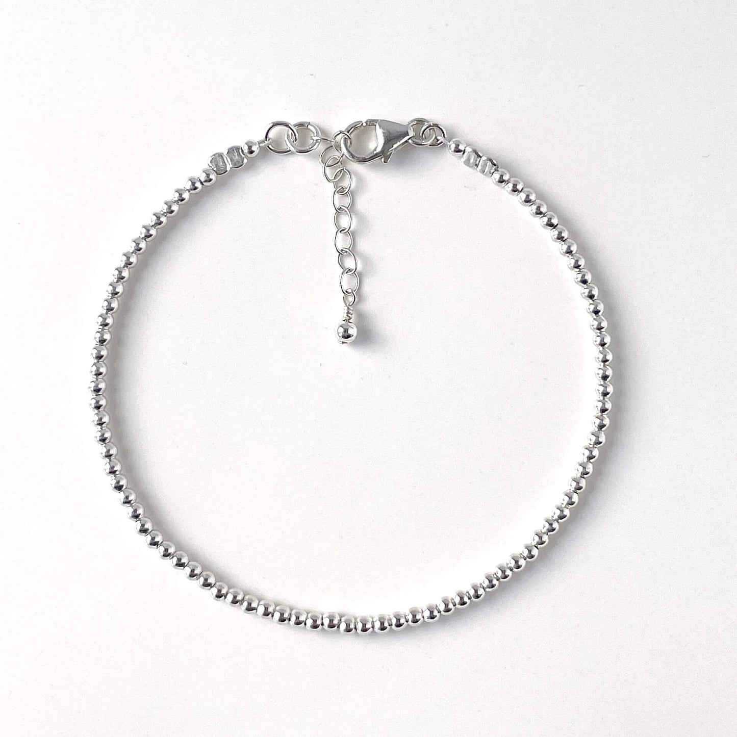 Minimalist sterling silver bead bracelet with 2mm beads on a white background